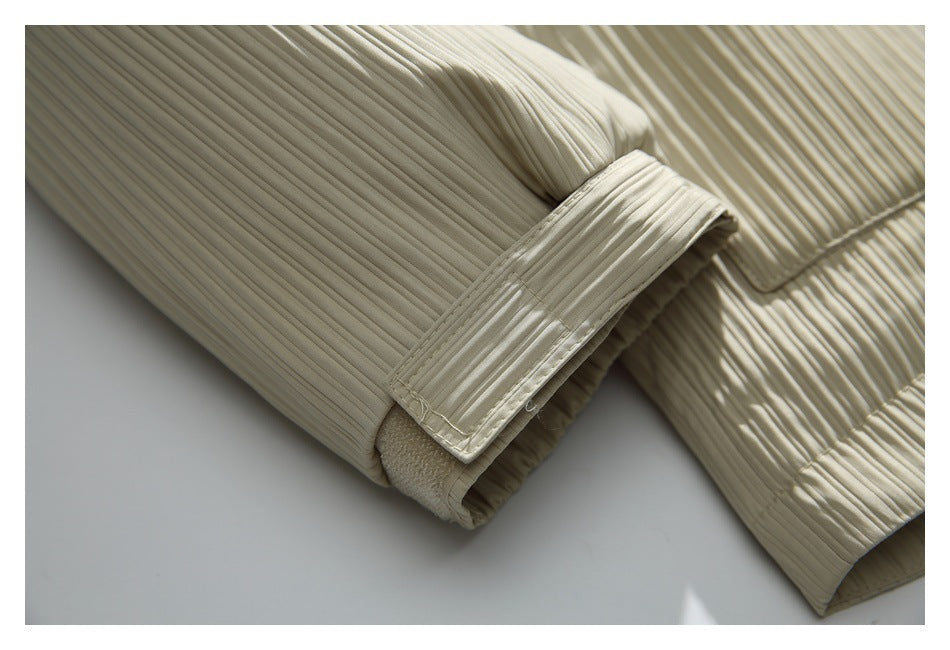 Close-up of a pleated sleeve cuff with an adjustable strap on the ivory jacket.