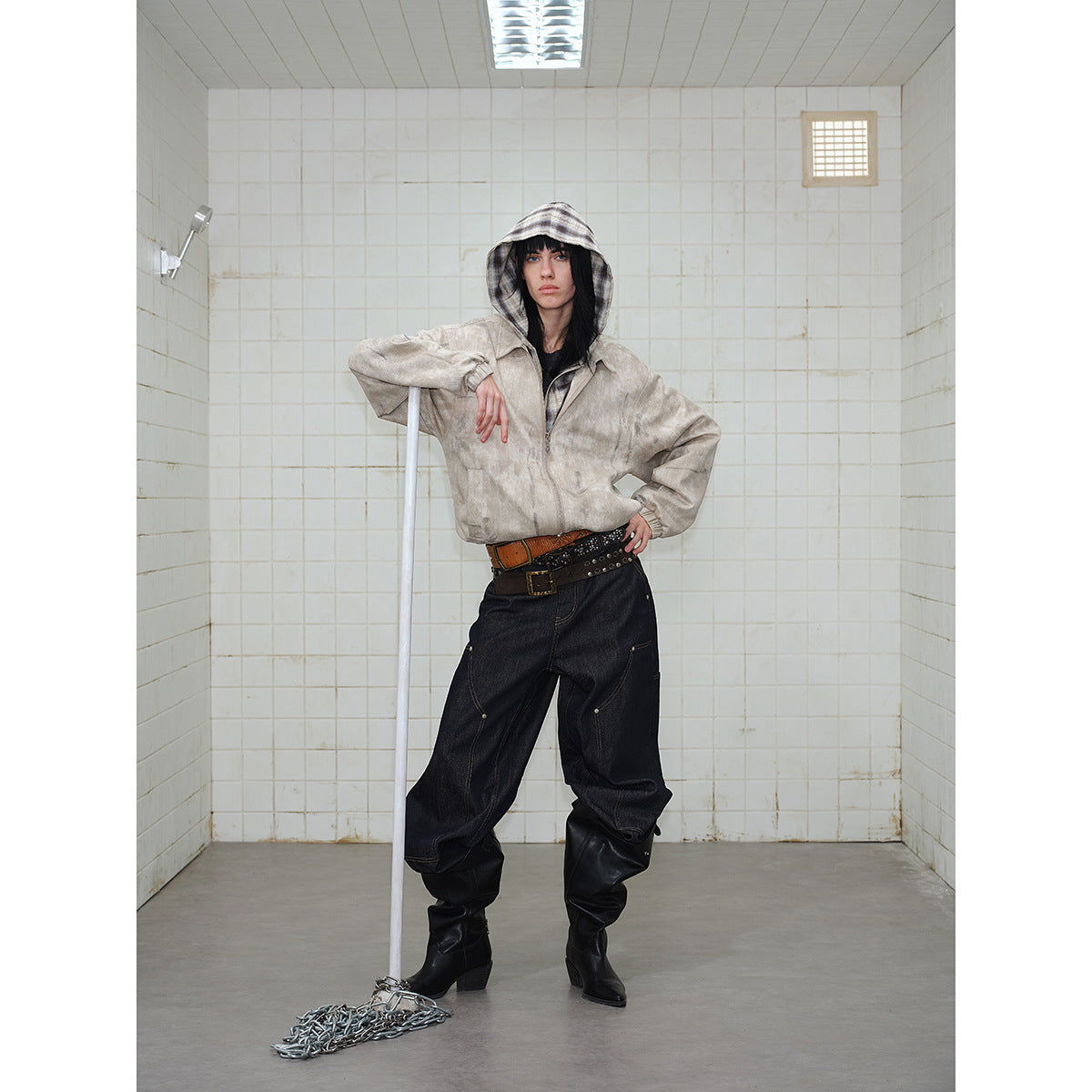 Full-length model wearing a beige plaid-hooded jacket, wide dark jeans and black boots.