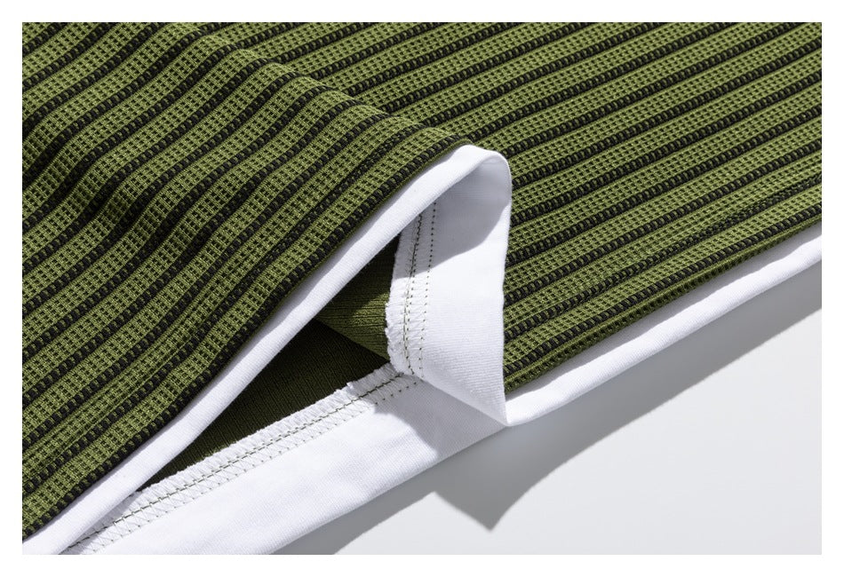Close-up showing the white inner layer and stitching beneath the olive-green and black striped garment.