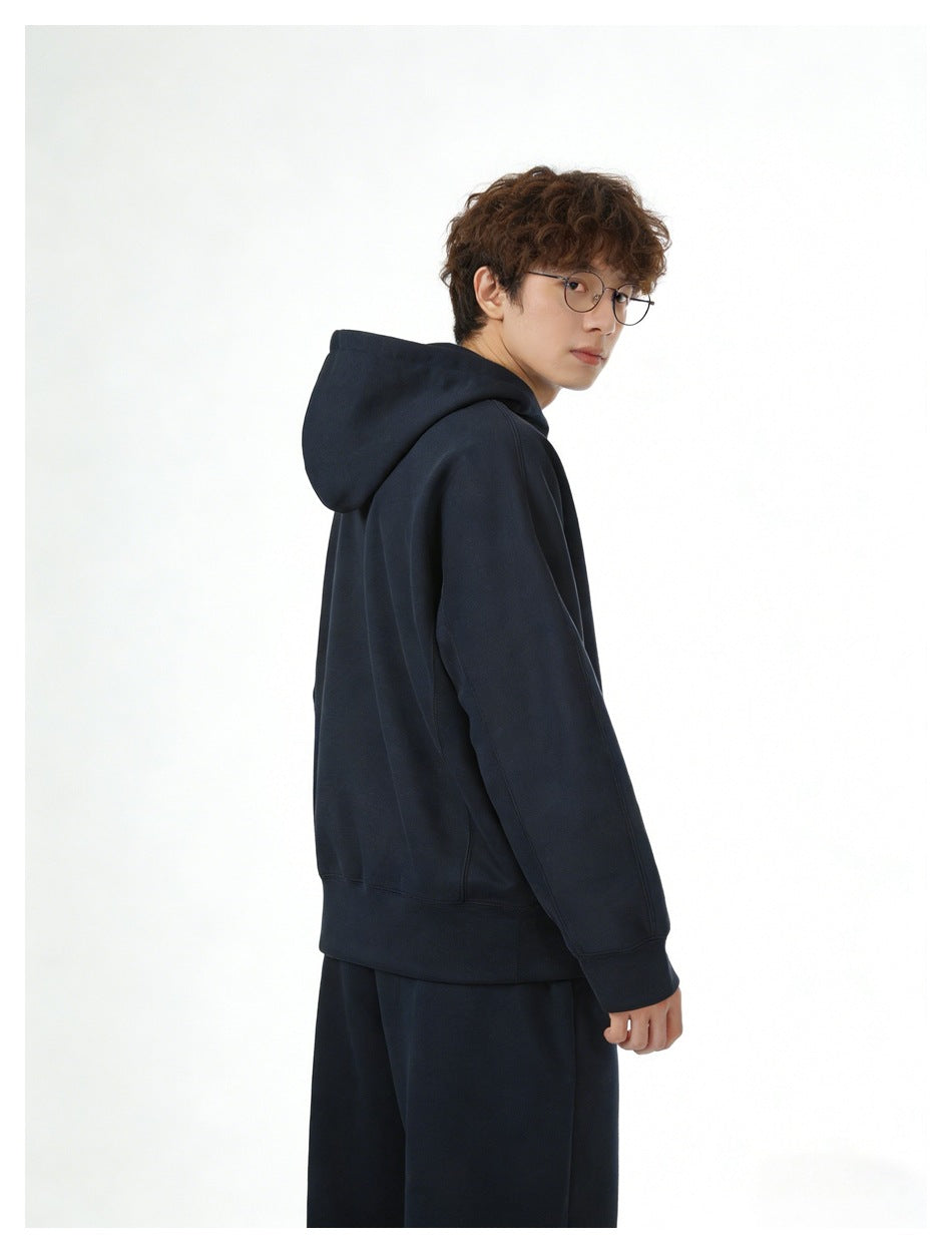 Model in a navy hooded sweatshirt and matching pants, shown from the side and back.