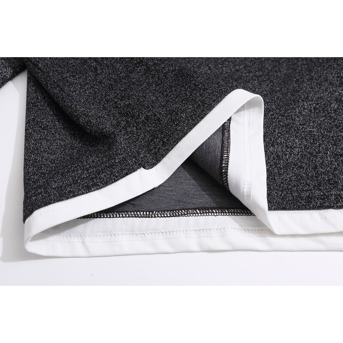 Close-up of the top's charcoal heather fabric and white-trimmed hem with visible stitching.