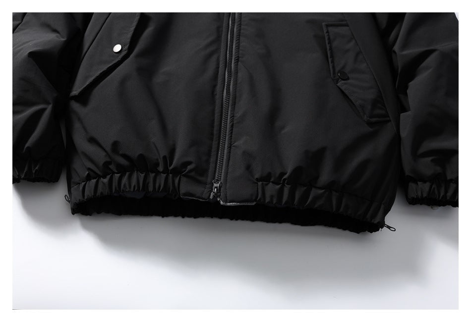 Close-up of the black jacket's zippered lower front, snap-flap pockets, and elasticized hem.