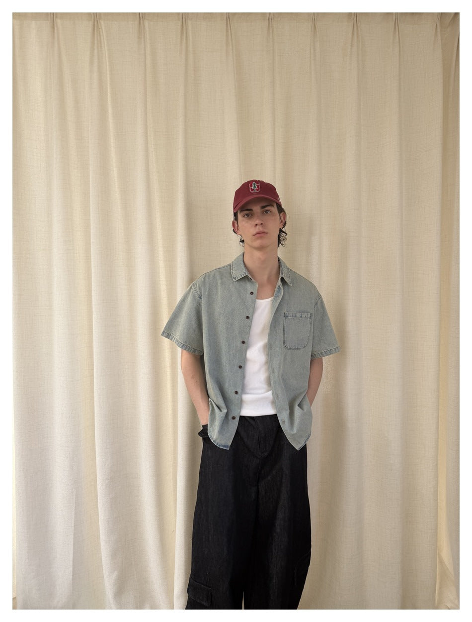 Front view of a model wearing an open light blue short-sleeve shirt over a white top and wide black trousers.