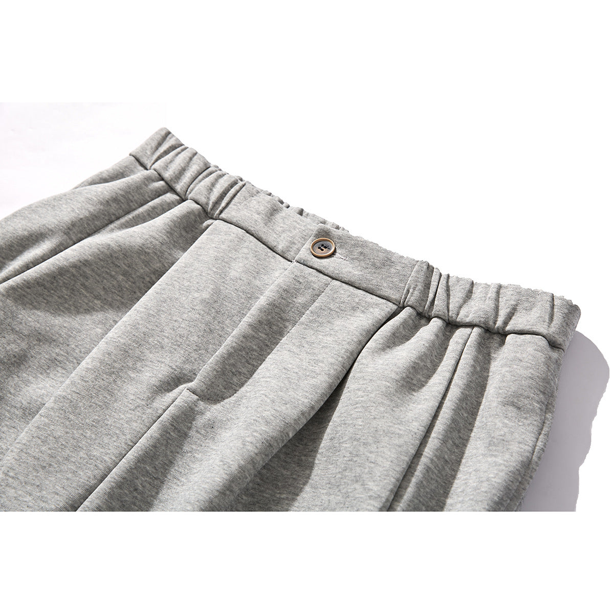 Close-up of heather gray trousers showing a pleated waistband and front button.
