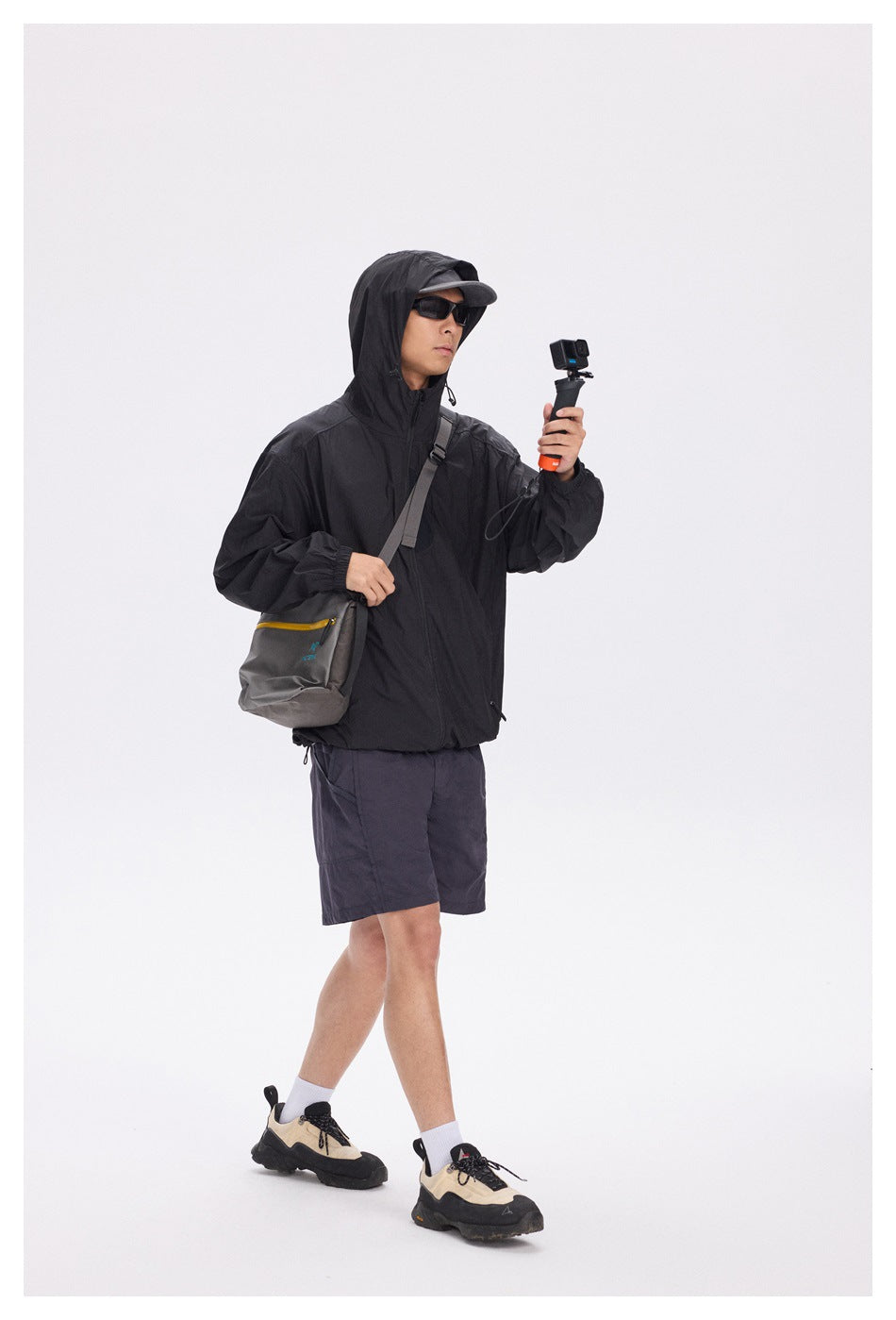 Full-length view of a model wearing a black hooded zip jacket with dark shorts.