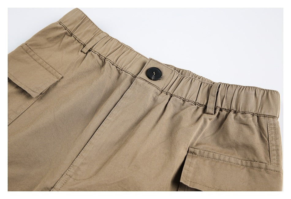 Close-up of khaki cargo pants showing the elastic waistband, button closure and flap pockets.