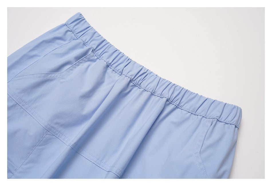 Close-up of the light blue skirt's gathered elastic waistband and stitched pocket opening.