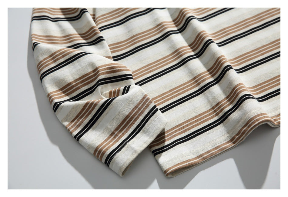 Close-up of a cream striped shirt sleeve and stitched edge in black and brown.
