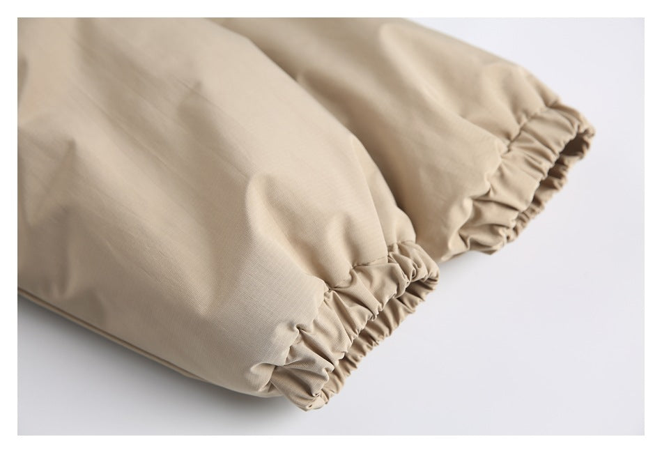 Close-up of beige garment fabric with two gathered elastic cuffs.