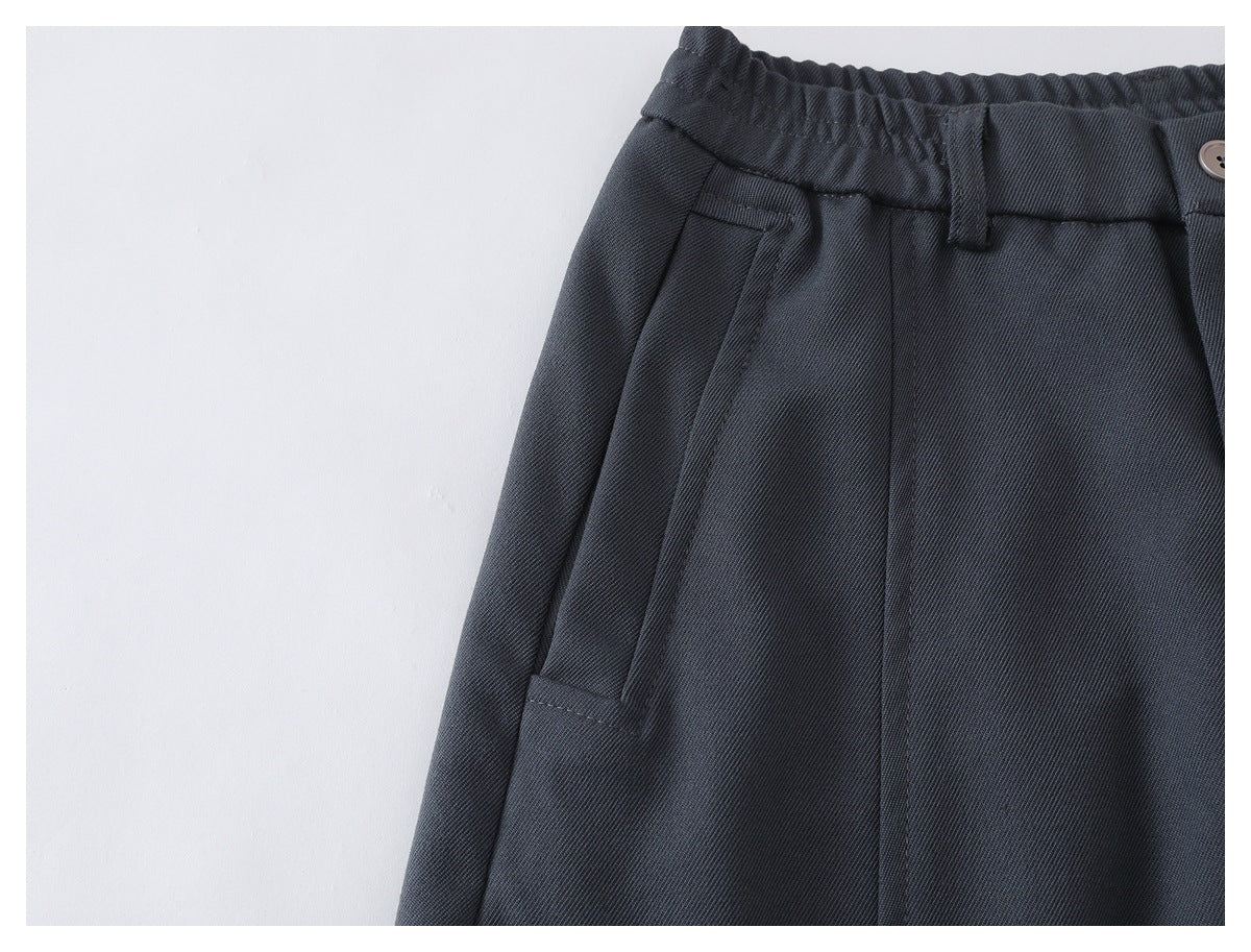 Close-up of charcoal trousers showing the front waistband, belt loop, and slanted pocket.