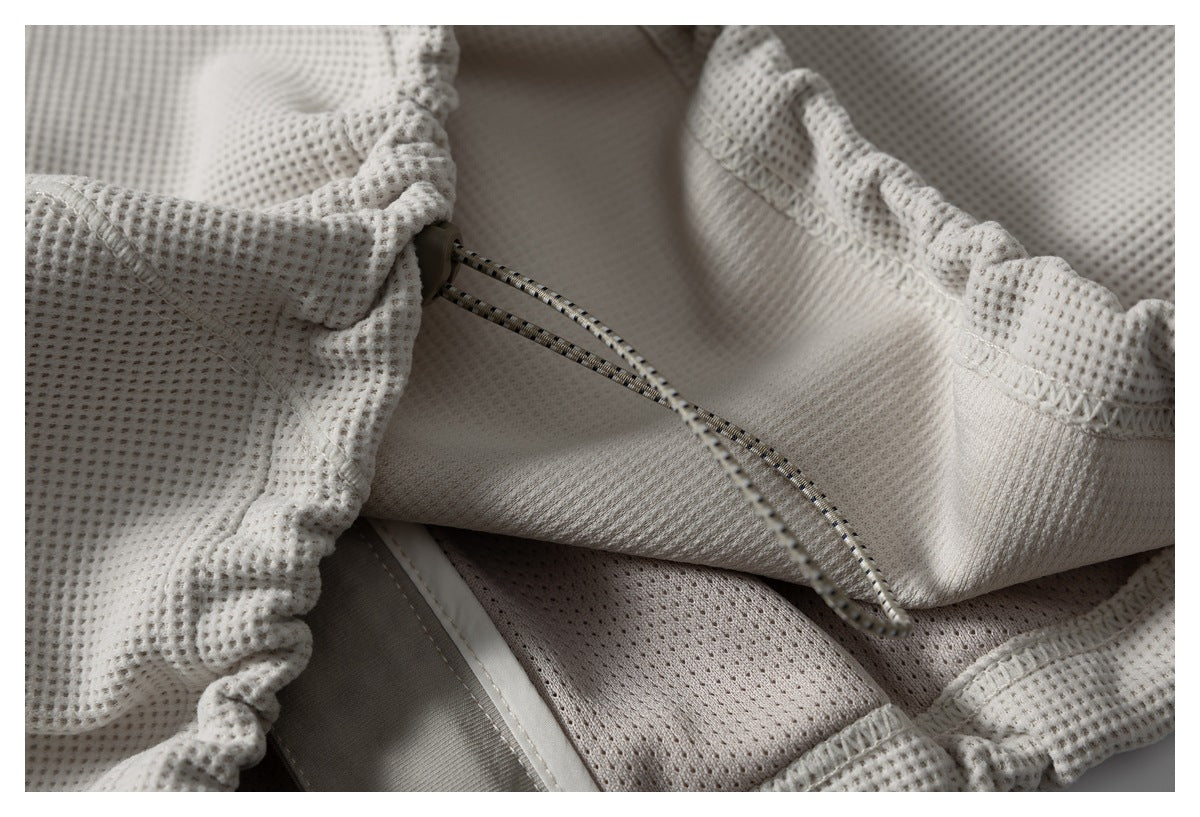 Interior close-up of a pale gray garment's gathered waistband and striped drawcord.