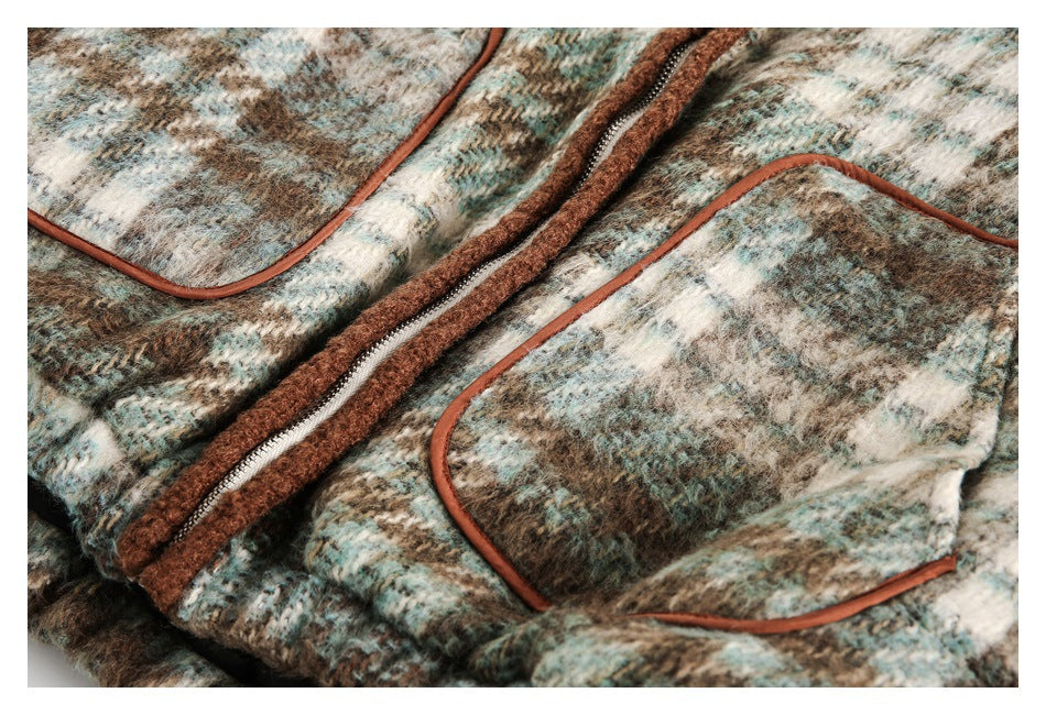 Close-up of the jacket’s front zipper and patch pocket with brown trim against plaid fabric.