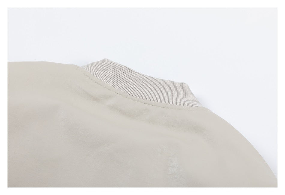 Close-up of the rib-knit stand collar and upper shoulder of a light beige jacket.