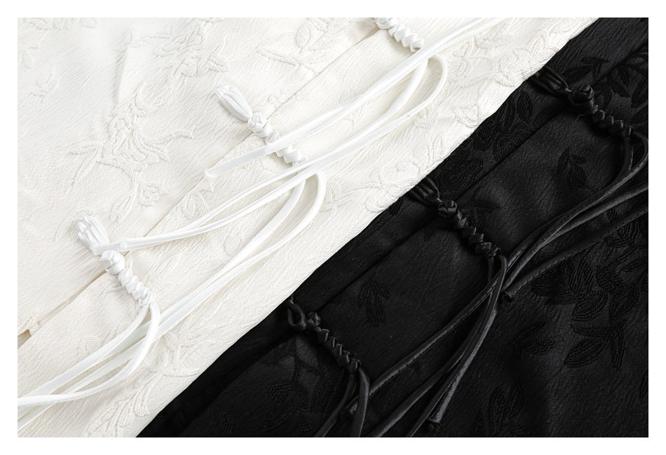 Close-up of ivory and black shirts showing textured floral patterns and matching knotted cord closures.