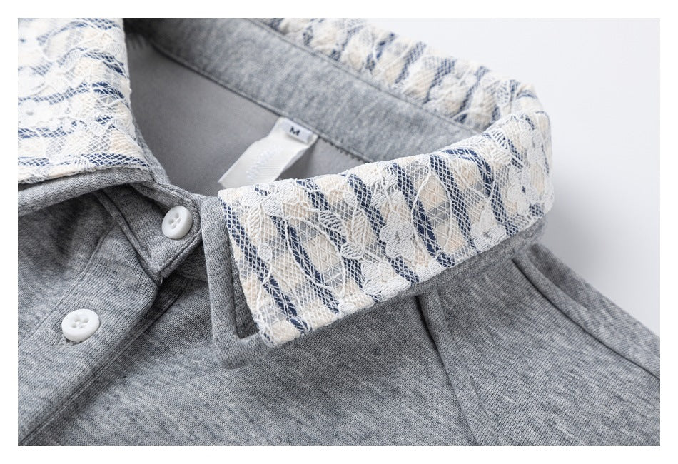 Close-up of a gray top with a white and navy floral lace collar and white buttons.