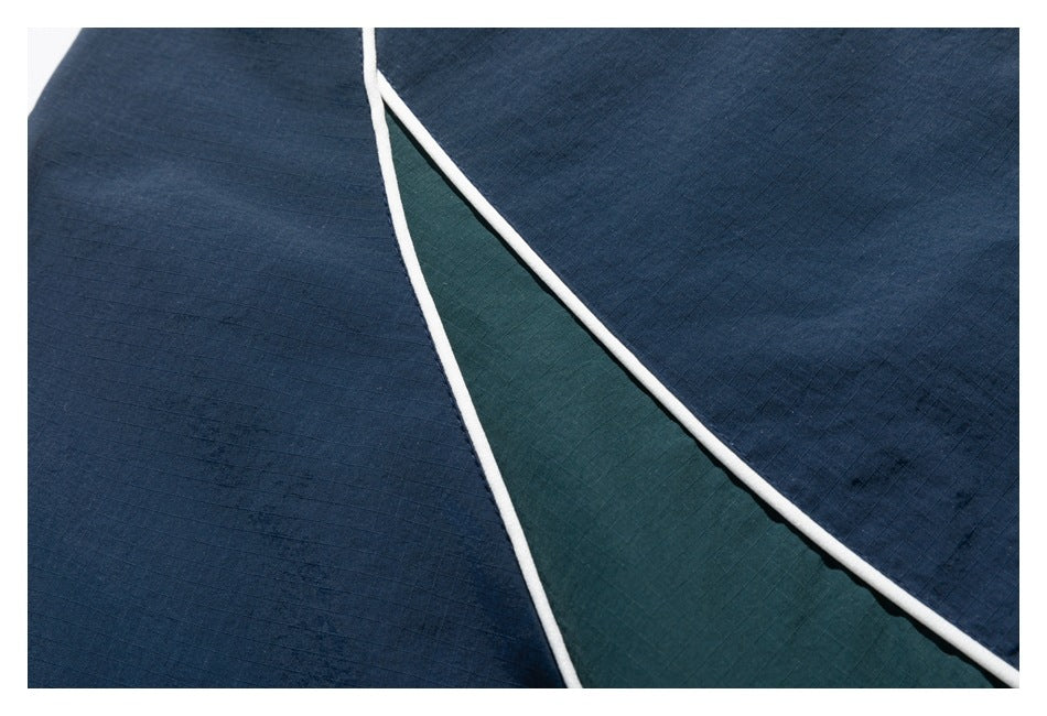 Close-up of navy jacket panels with a dark green inset bordered by white piping.