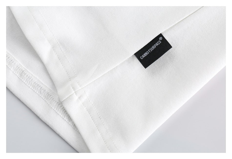 Close-up of a white garment hem with stitching and a small black woven brand label.