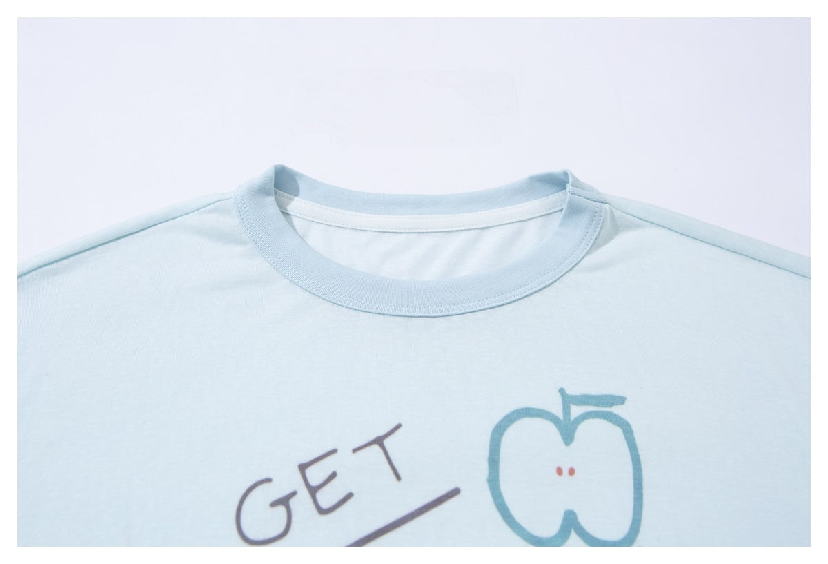 Close-up of a pale blue T-shirt's crew neck and upper chest, with part of a colorful printed design visible.