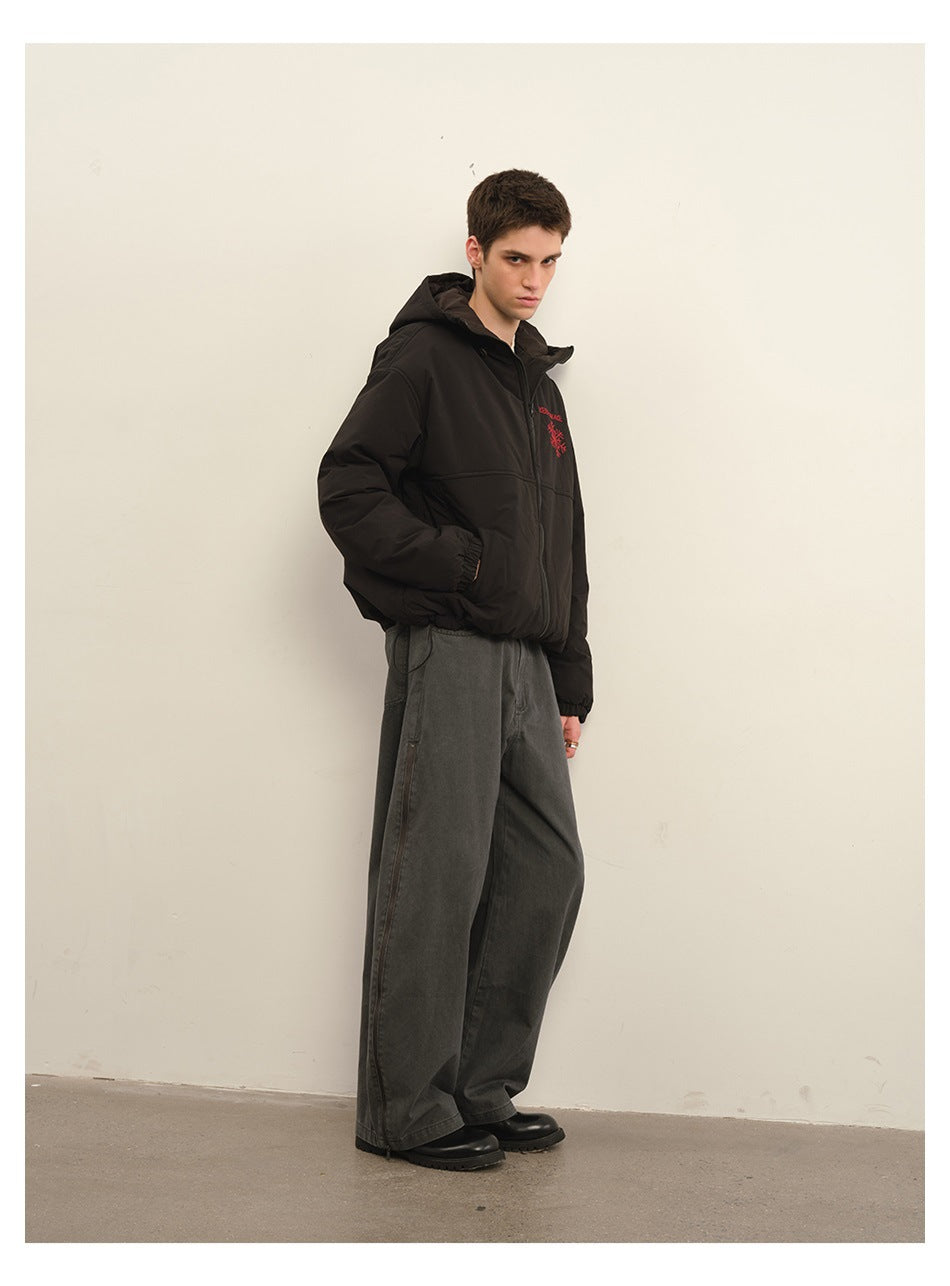 Model wearing washed gray wide-leg pants with a black hooded jacket, side zipper visible, standing against a wall
