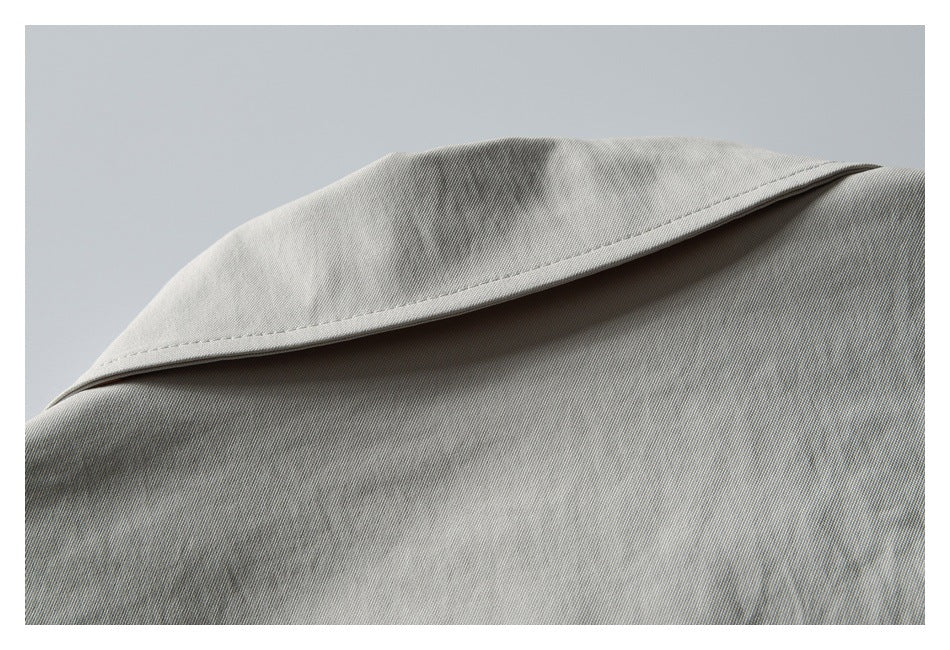 Close-up of the light gray jacket's pointed collar and stitched shoulder area.