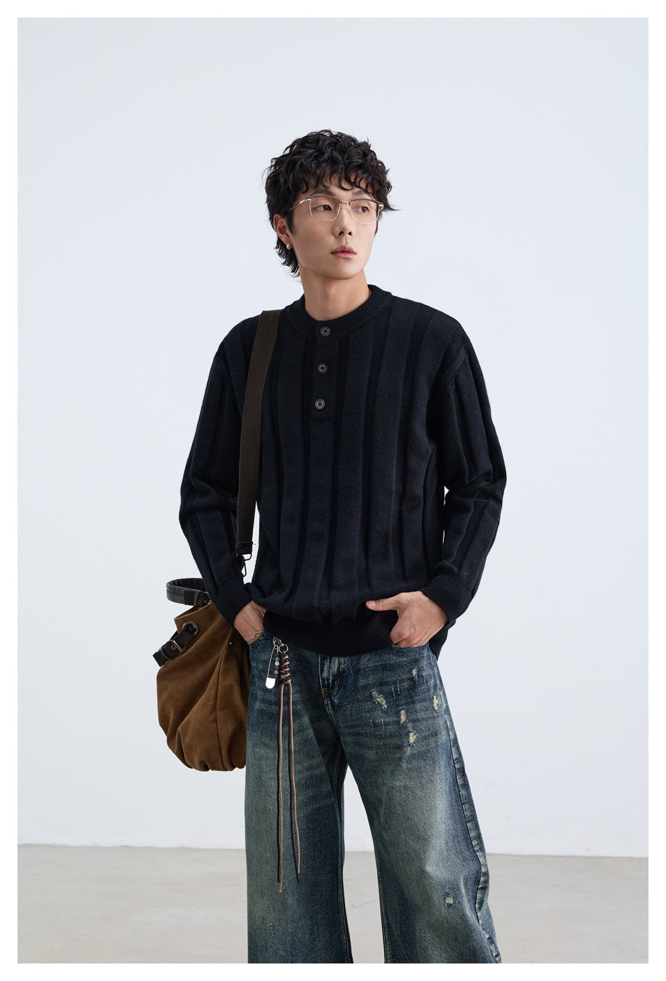 Model wearing black ribbed button-placket sweater with a brown shoulder bag and distressed jeans, close-up view