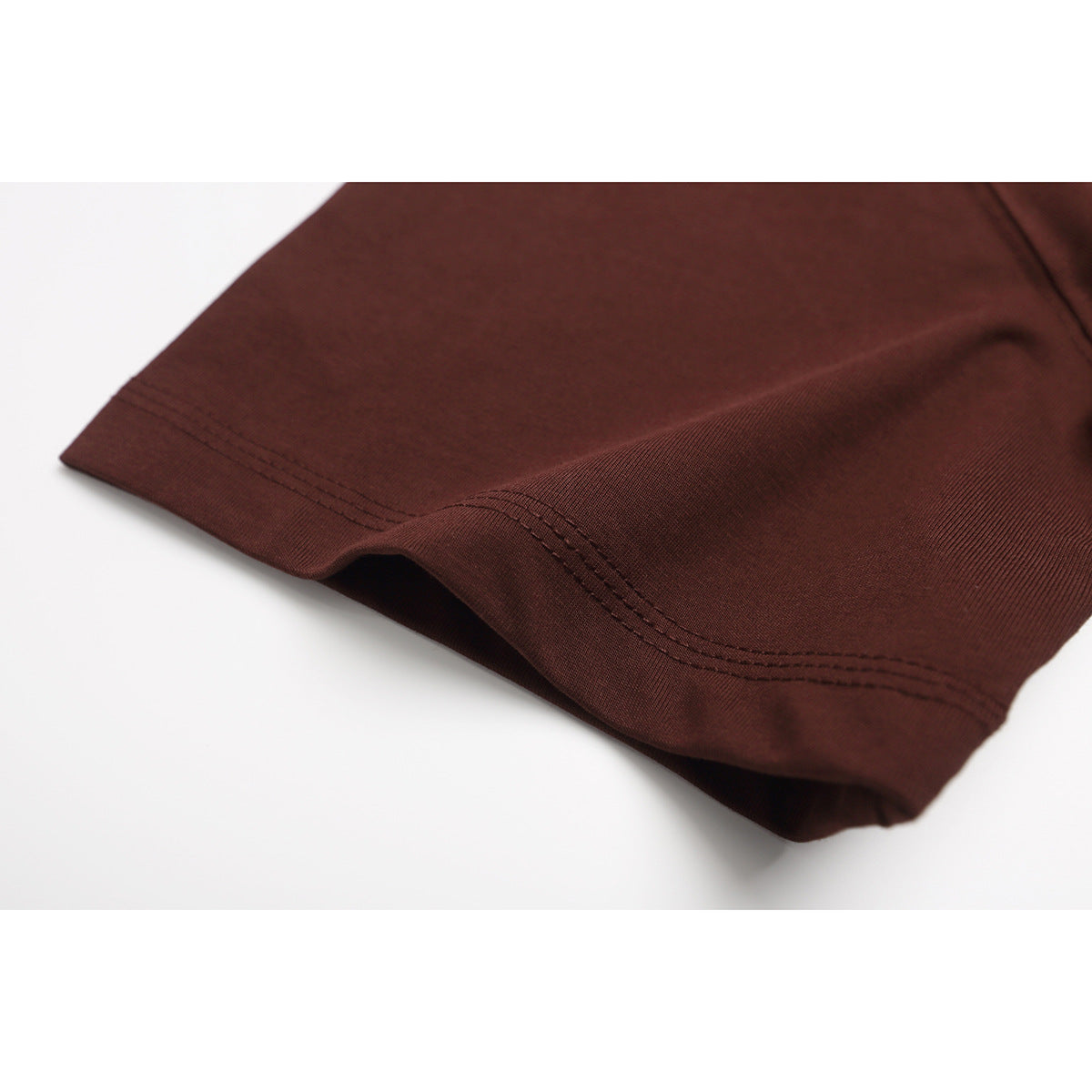 Close-up of a burgundy T-shirt sleeve edge with parallel rows of stitching.