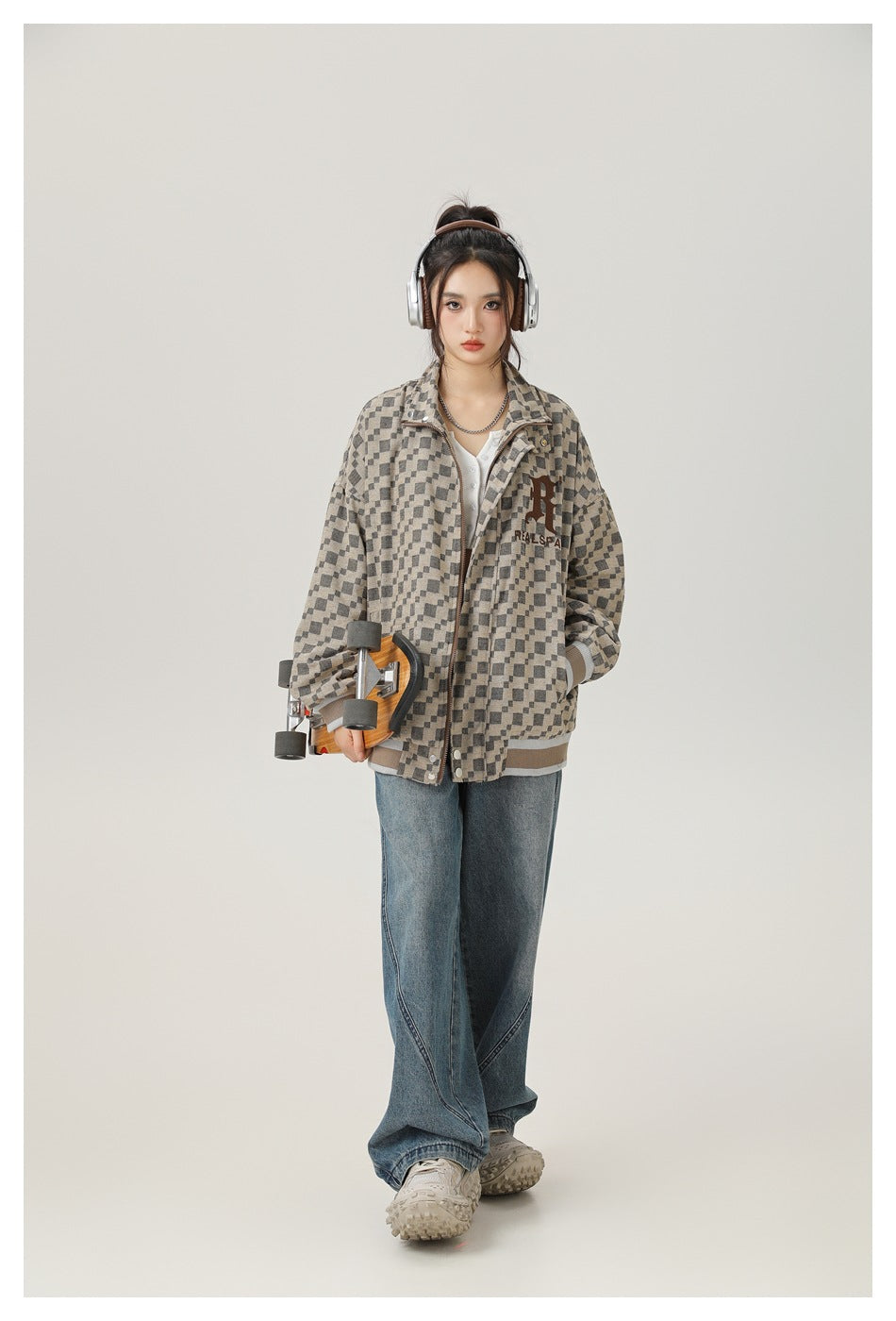 Model wearing an open checkered jacket over a white top with wide-leg jeans, holding a skateboard and wearing headphones
