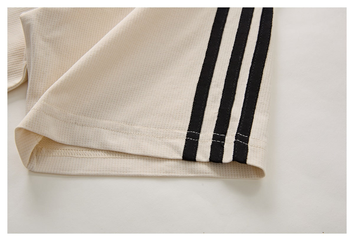 Close-up of a cream garment sleeve with three black stripes near the cuff.