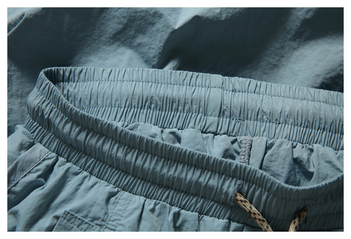 Close-up of the blue-gray garment’s gathered elastic waistband, stitching, and drawcord.