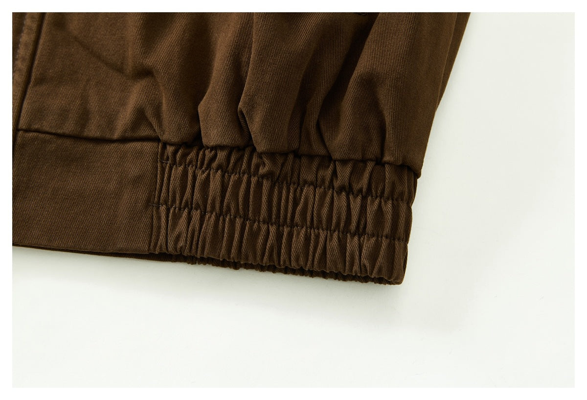 Close-up of the dark brown jacket's gathered elastic hem and stitched panel seam.