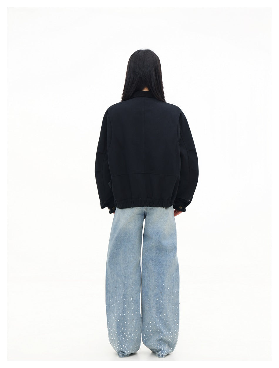 Back view of a model wearing a black jacket with a gathered hem and light-blue embellished wide-leg jeans.