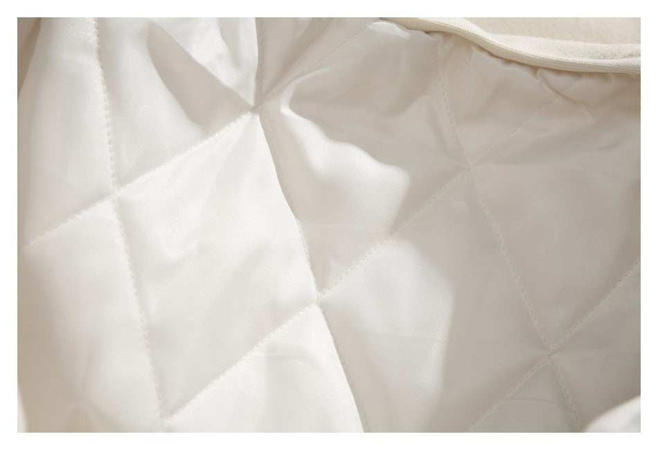 Close-up of smooth ivory quilted garment lining with stitched panels and bound edge.