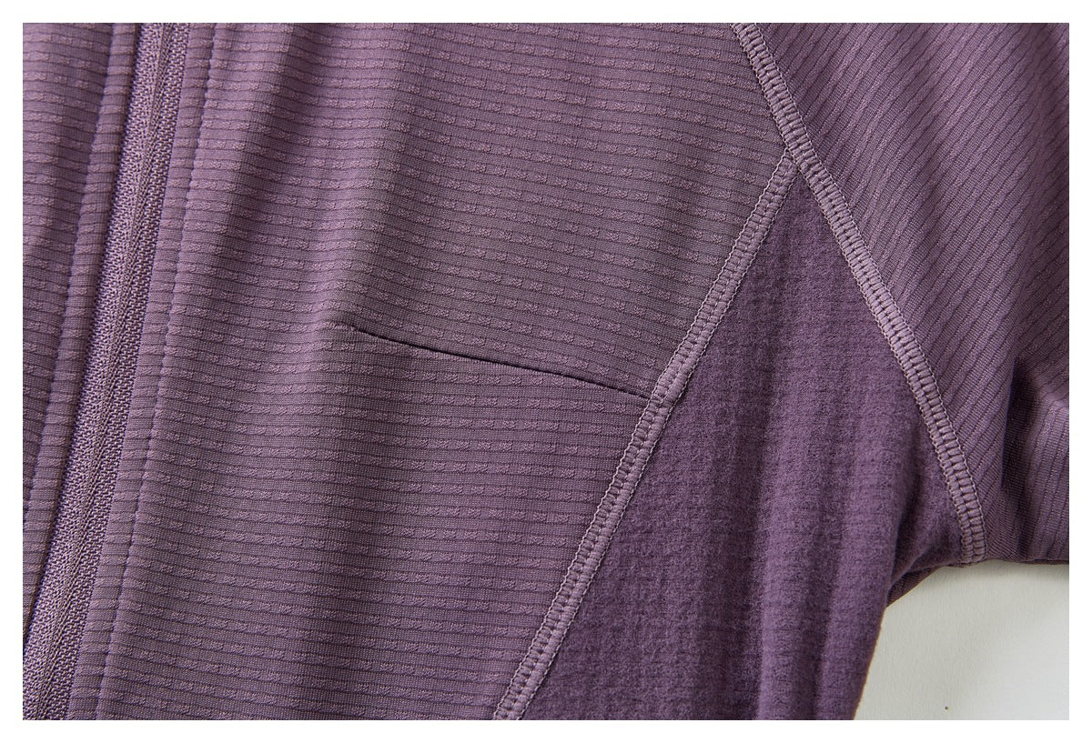 Close-up of a purple jacket showing its ribbed front, zipper, curved seams, and contrasting underarm panel.