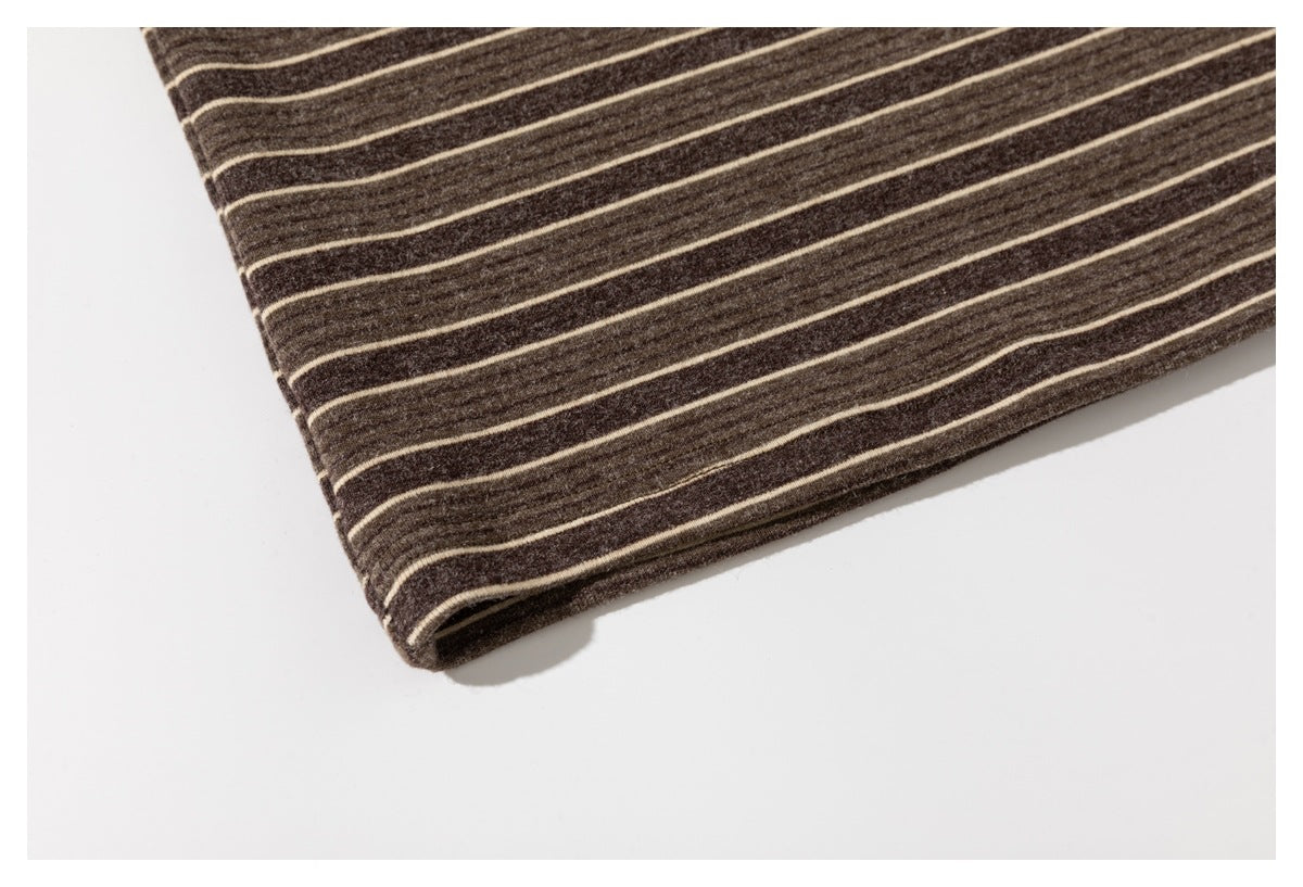 Close-up of the lower hem of a dark brown shirt with thin cream stripes.