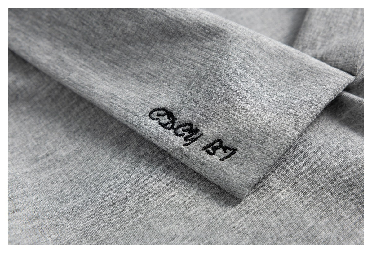 Close-up of black embroidered lettering on heather gray fabric.