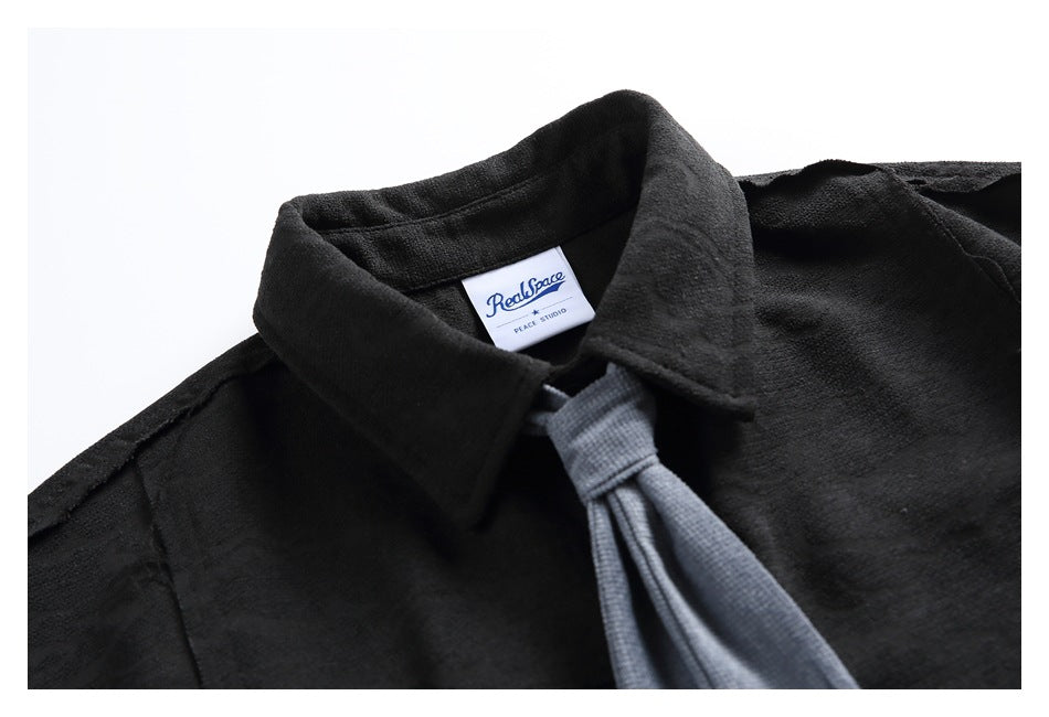 Close-up of a black shirt collar, gray tie, and visible RealSpace Peace Studio neck label.