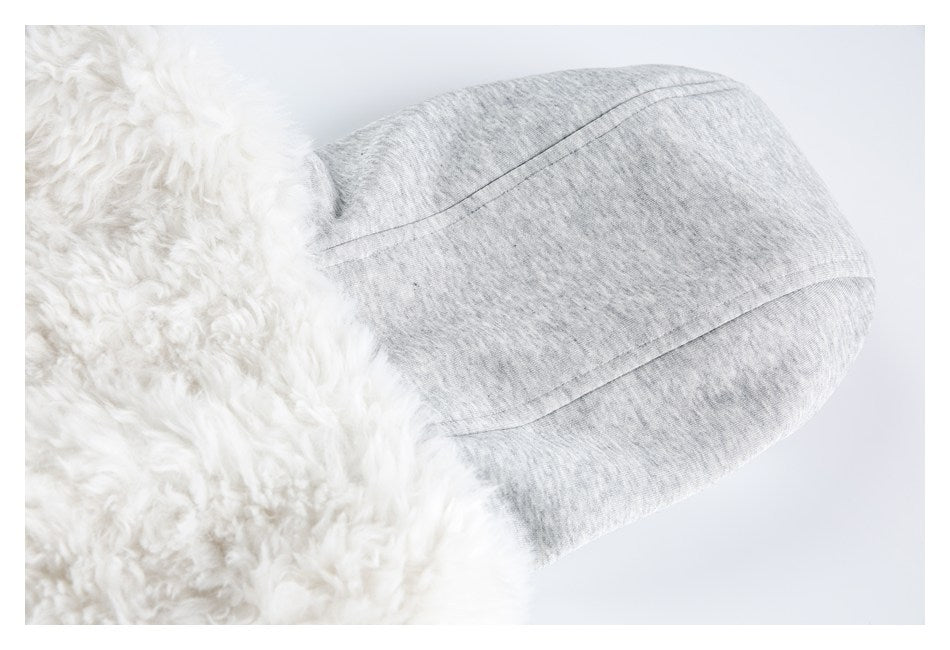 Close-up of white shaggy trim beside a curved seam and heather-gray fabric panel.