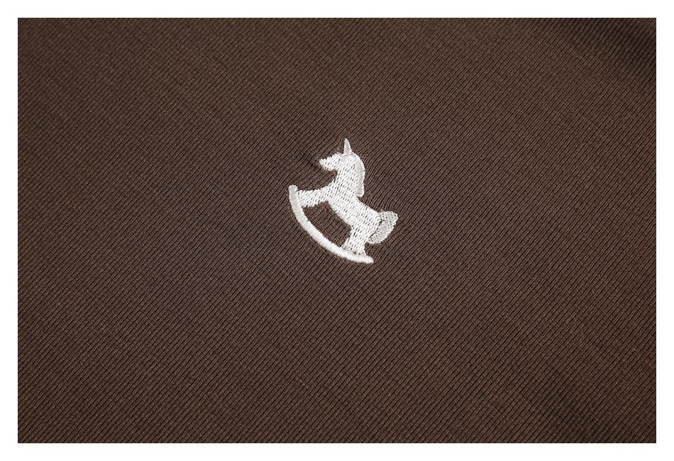 White rocking-horse embroidery centered on brown fabric.