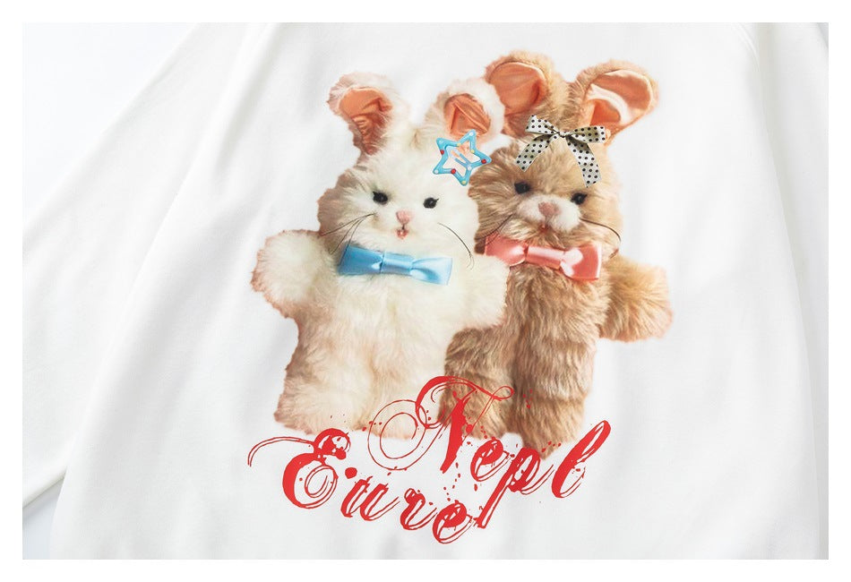 Cropped front view of a white sweatshirt with a graphic of two fluffy animals in bows and red script lettering.