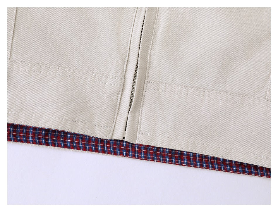 Close-up of the jacket hem, zipper and lower stitching, showing a red and navy plaid lining edge.