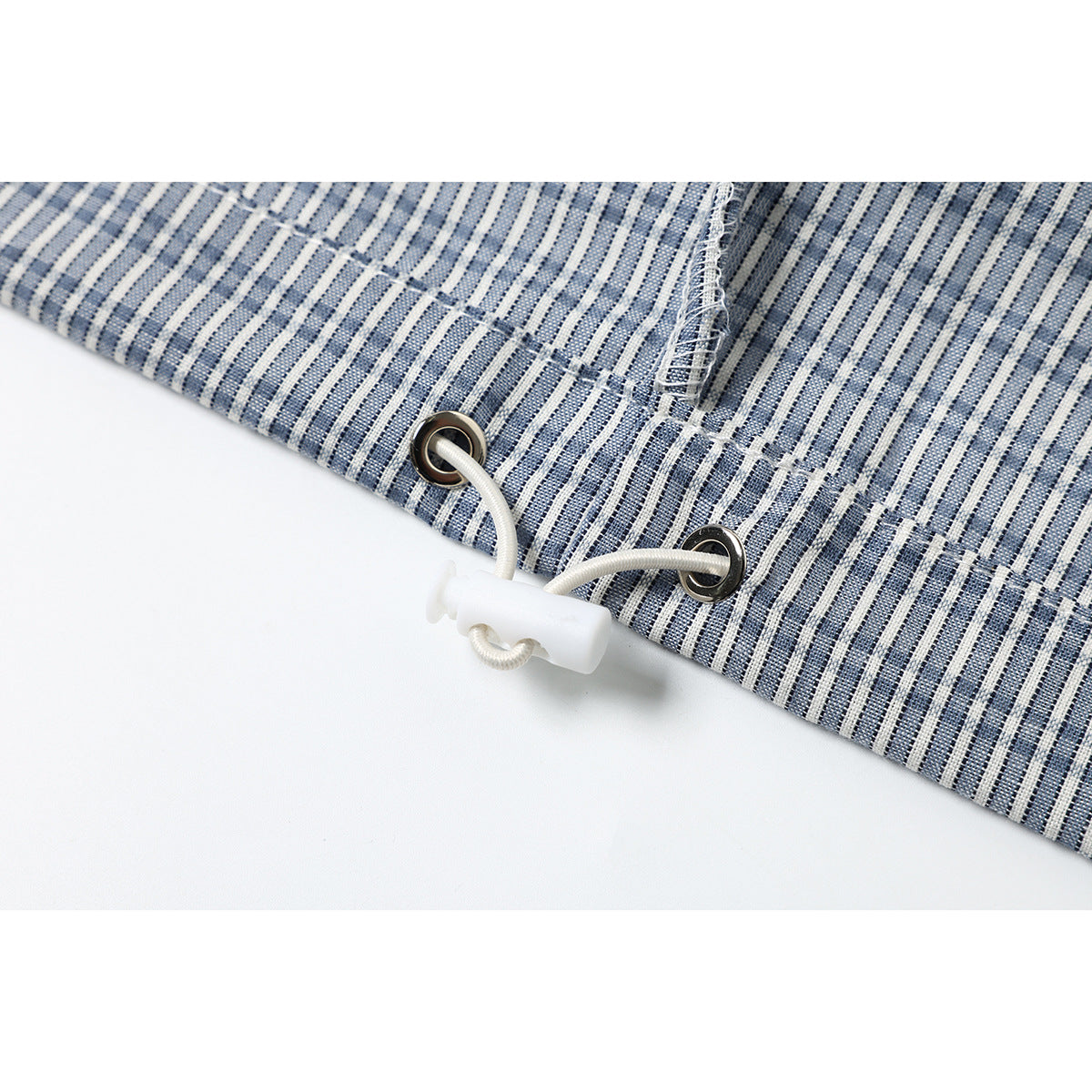 Close-up of the checked shirt hem with metal eyelets and a white drawcord toggle.