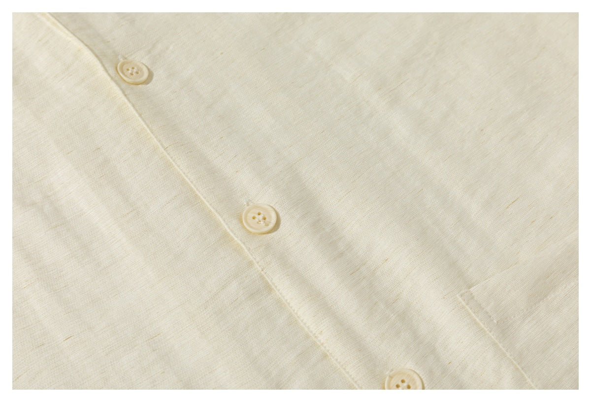 Close-up of the cream shirt's button placket and lightly textured fabric.