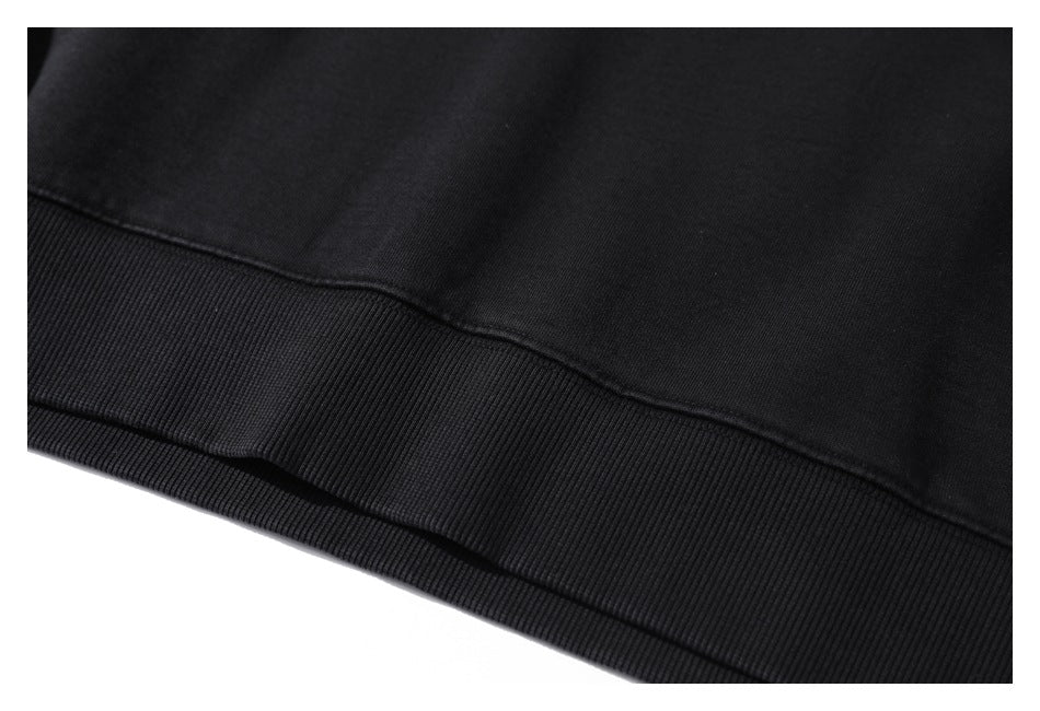 Close-up of the ribbed lower hem and stitching on a black garment.