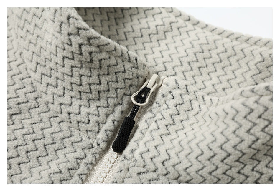 Close-up of a cream and gray zigzag-patterned garment with a white zipper and black pull tab.