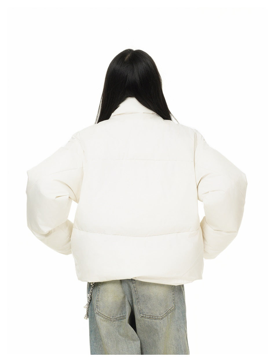 Rear view of a person wearing an ivory padded jacket with horizontal panels and loose blue-gray jeans.
