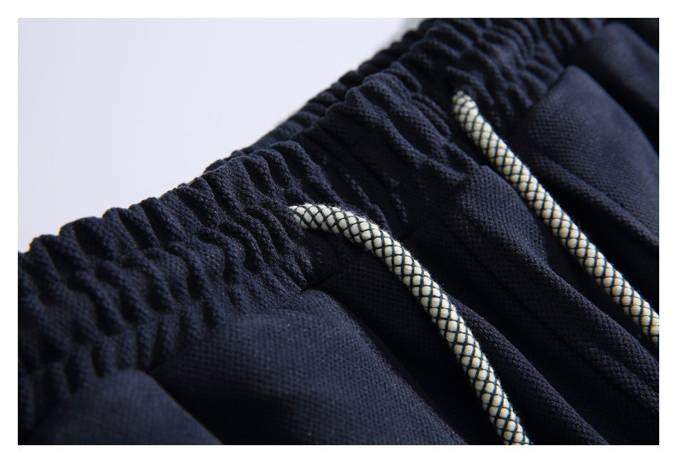 Close-up of navy pants showing the gathered elastic waistband and patterned drawcords.