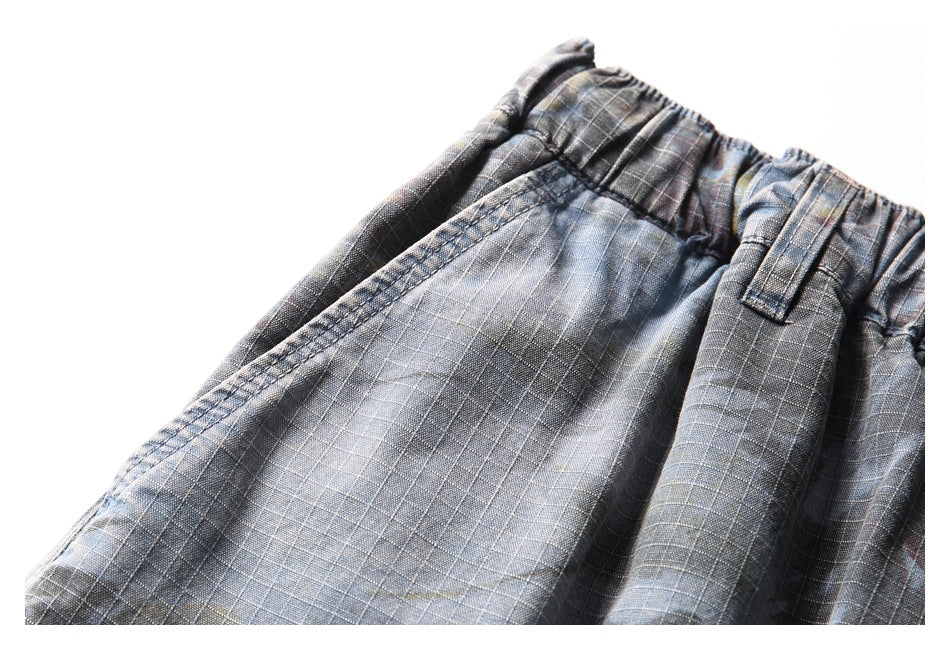Close-up of the elastic waistband and belt loop on dark gray plaid trousers.