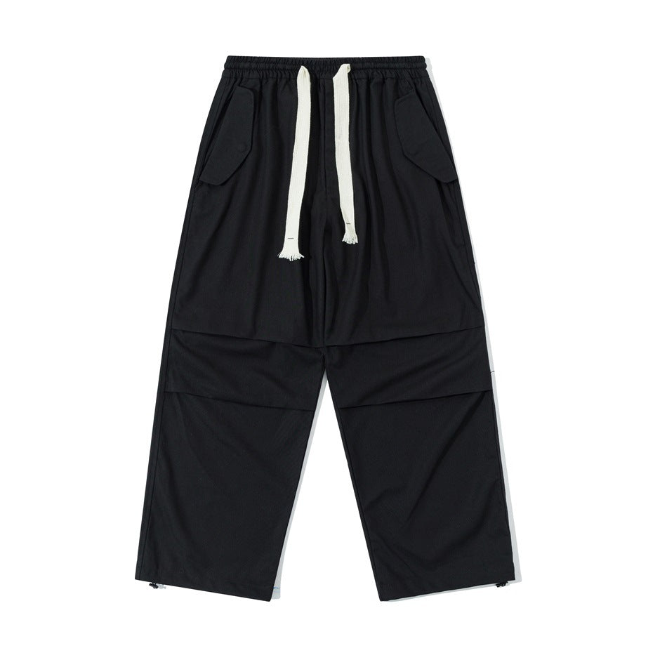 Black wide-leg drawstring pants with hip flap pockets, knee pleats and hem toggles, front flat view