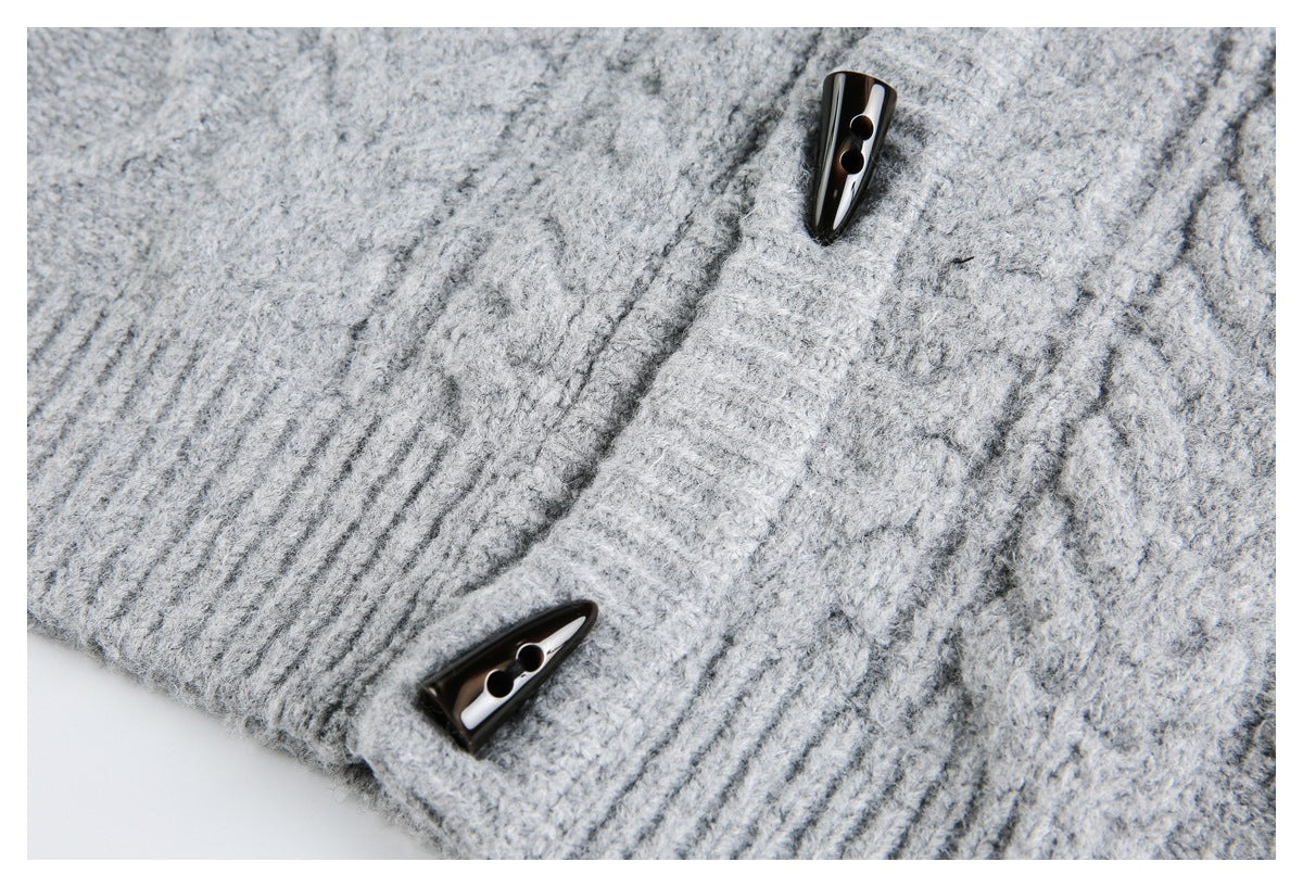 Close-up of a light gray knit garment with two glossy dark toggle buttons and ribbed trim.