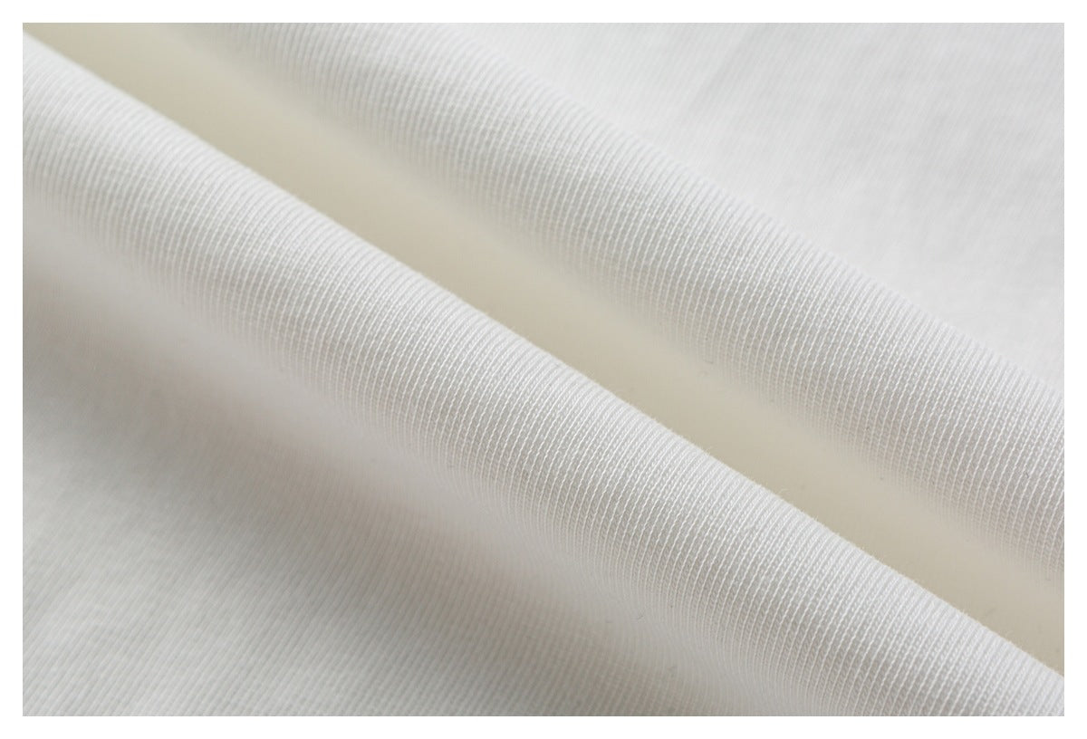 Macro view of white T-shirt fabric draped into soft folds, showing its knit texture.
